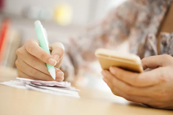 Woman hands with bills and mobile phone on table