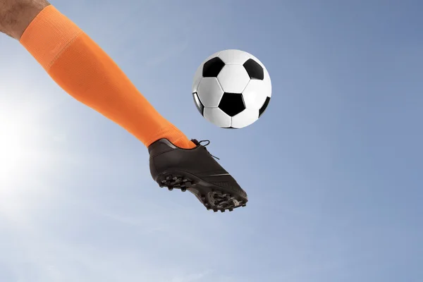 The soccer foot kicking ball on sky background