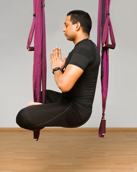 Man making aerial yoga exercises, indoor