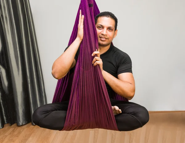 Man making aerial yoga exercises, indoor