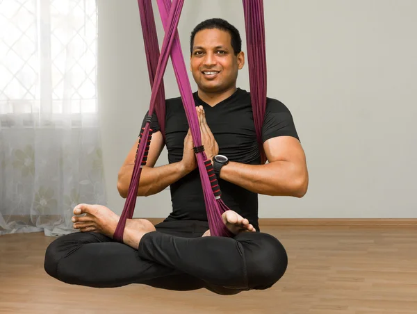 Man making aerial yoga exercises, indoor