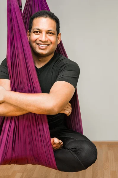 Man making aerial yoga exercises, indoor