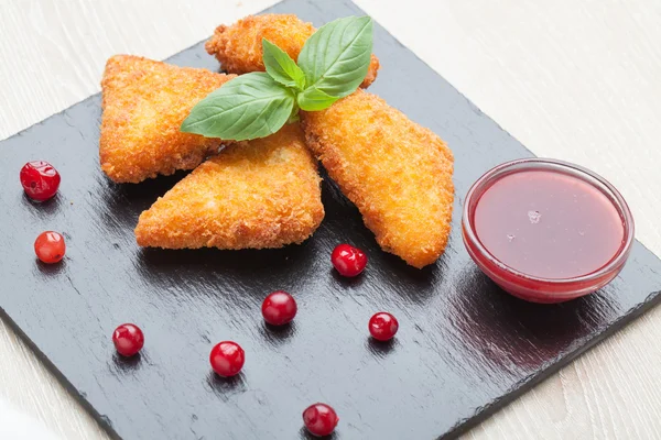 Fried cheese sticks served with cranberries, sauce on black ston