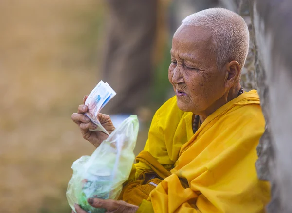 Female monk holding Cambodian money
