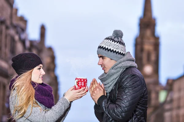 Young couple in love sharing a cup of hot drink on a cold winter