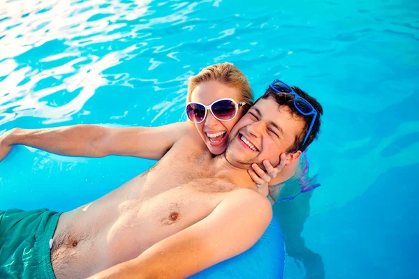 Couple with sunglasses in swimming pool.