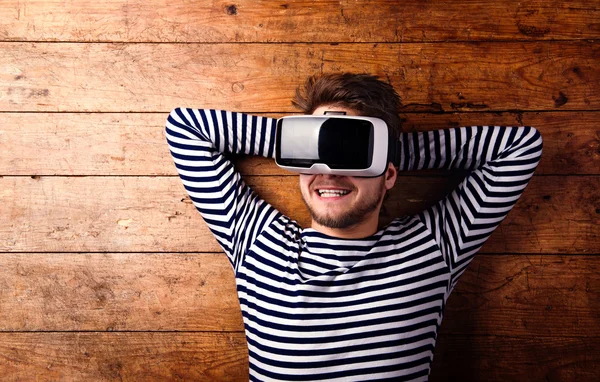 Man wearing virtual reality goggles. Studio shot, wooden background