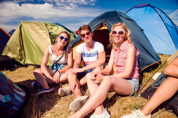 Teenagers sitting in front of tents