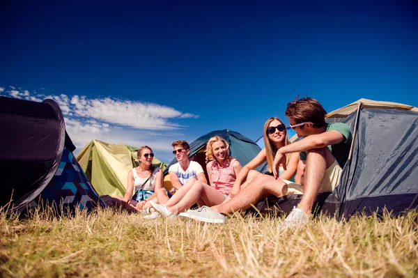 Teenagers sitting in front of tents