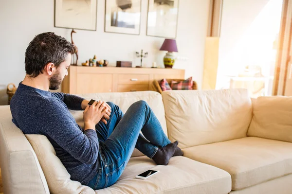 Man at home sitting on sofa using smart watch