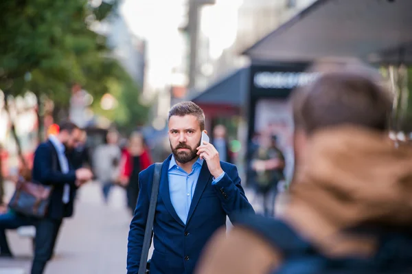 Hipster manager with smart phone walking in the street
