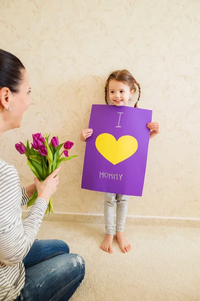 Mothers day, girl giving flowers and card to her mum