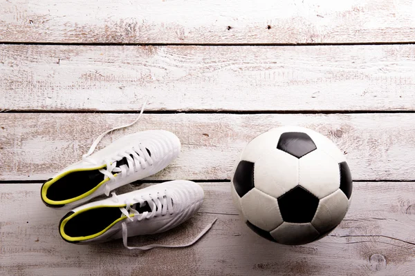 Soccer ball, cleats on wooden floor