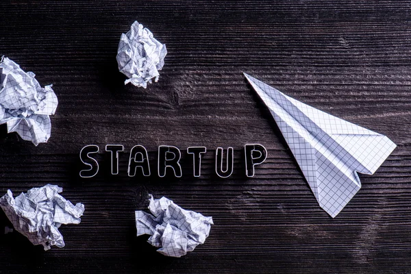 Desk, start up sign, airplane and crumpled paper balls
