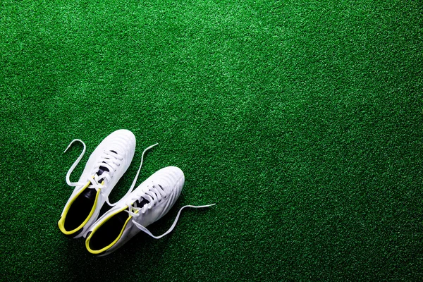 White cleats against green artificial turf, studio shot