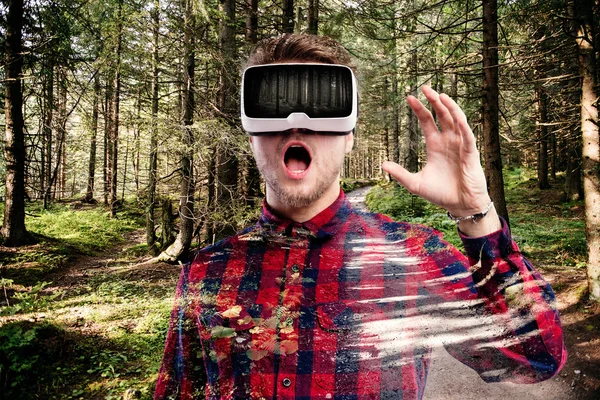 Man wearing virtual reality goggles. Green forest.