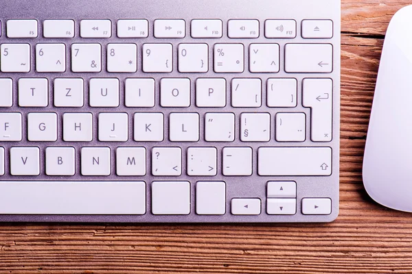 Computer keyboard and mouse laid on wooden desk