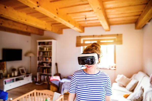 Woman wearing virtual reality goggles standing in living room