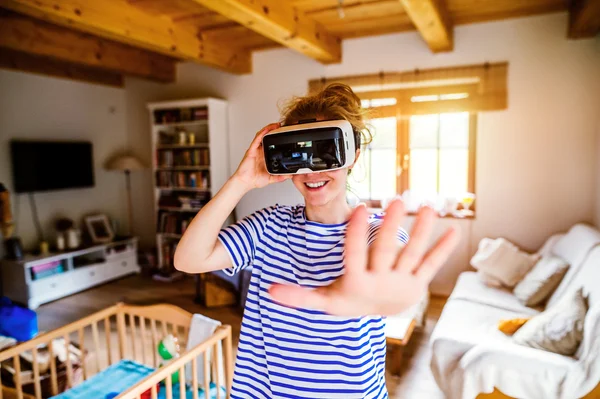Woman wearing virtual reality goggles standing in living room