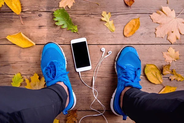 Runner in sports shoes. Smartphone and earphones.