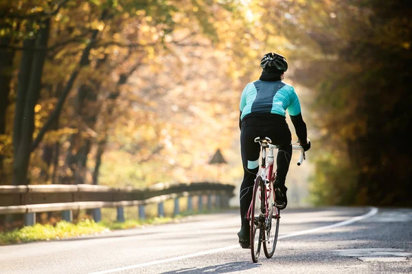 Sportsman riding bicycle in autumn