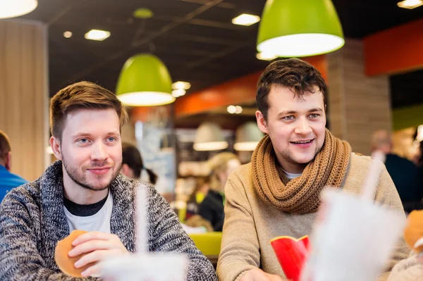 Two men eating out in fast food restaurant, talking