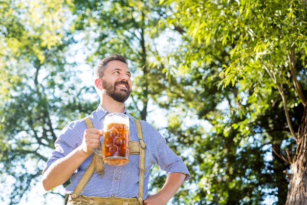 Man in traditional bavarian clothes holding mug of beer