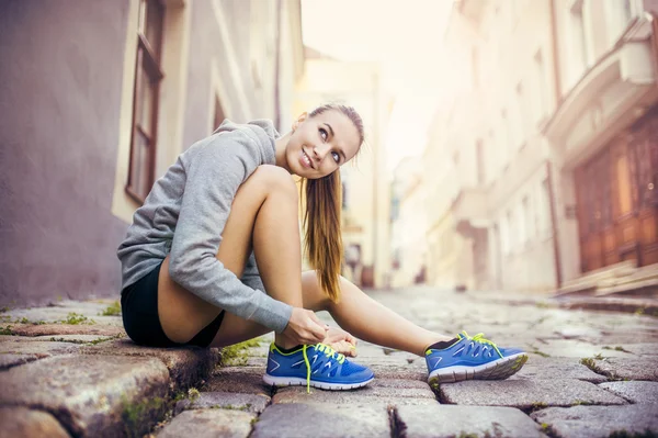 Female runner is tying her running shoes