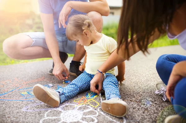 Little girl and parents drawing on the sidewalk