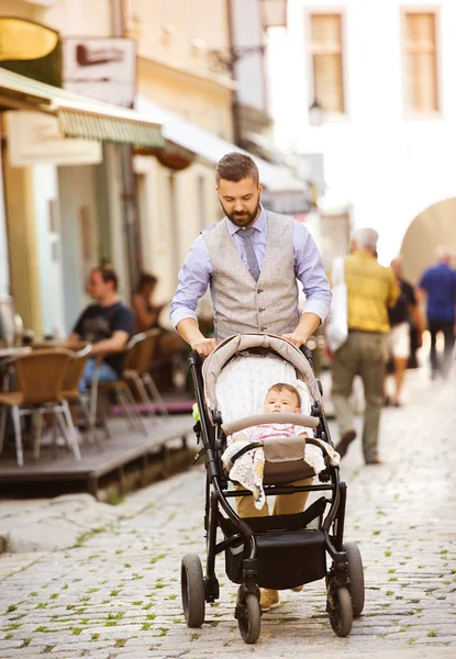 Man with beard walking with baby in pram