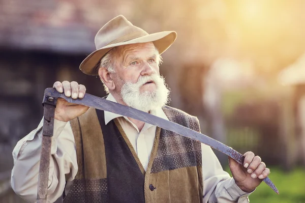 Old farmer with scythe taking a break