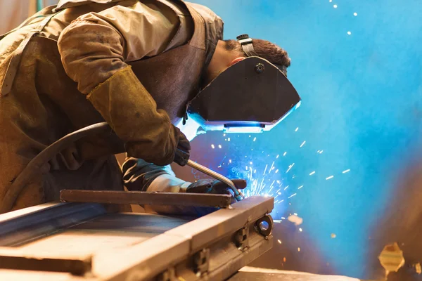 Man with protective mask welding in a factory