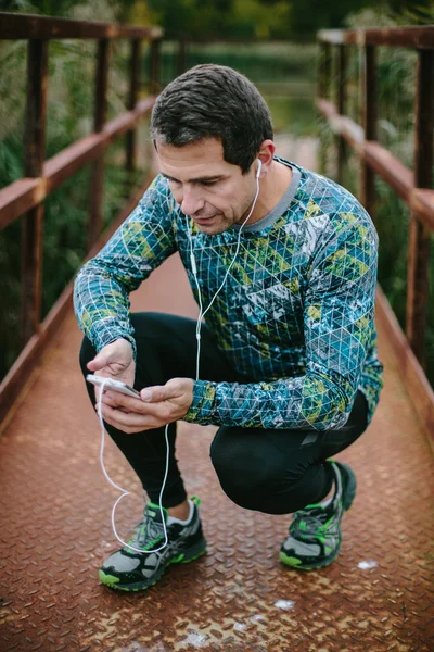 Runner on rusty bridge with smart phone listening music