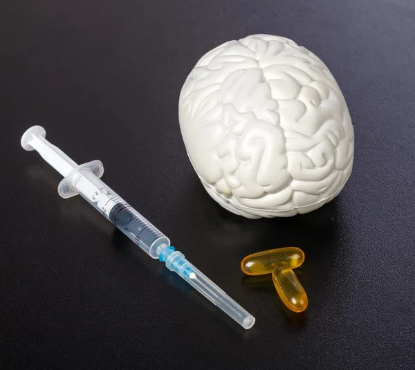 Plastic brain injection and omega 3 capsules on isolated black background