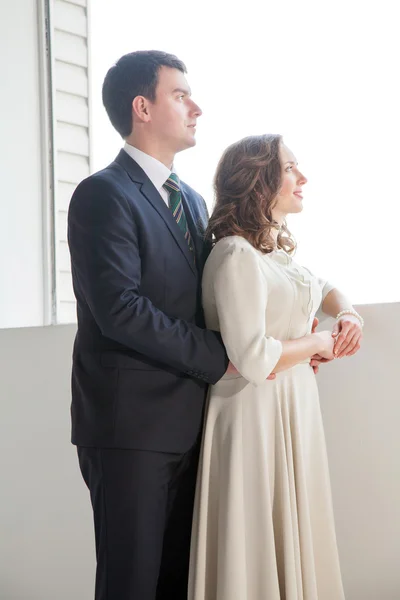 Happy wedding couple posing in bright room embracing each other