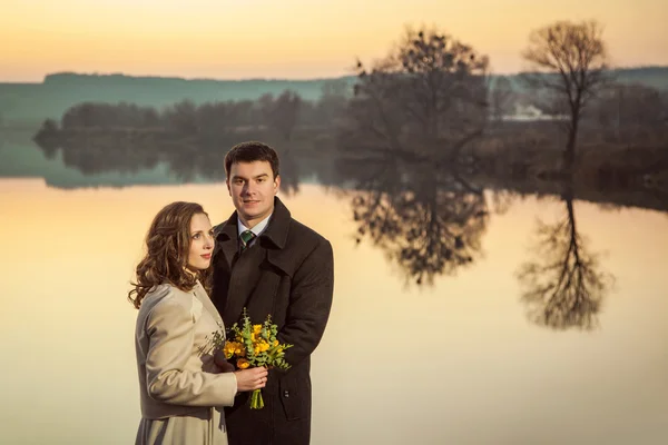 Young wedding couple enjoying romantic moments in autumn lake.