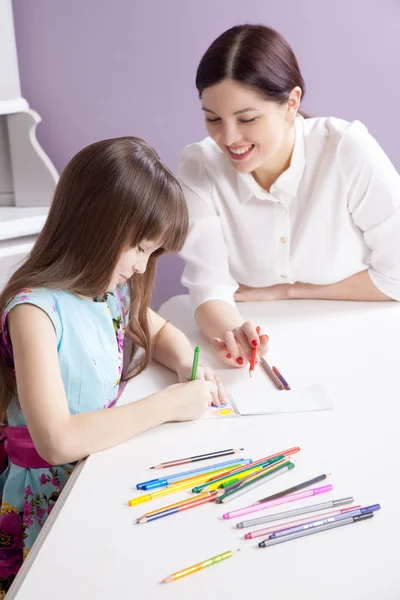 Happy mother teach her daughter to paint.
