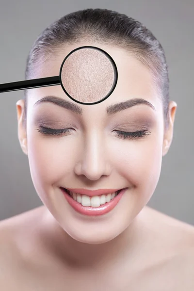Skin care and beauty concept - face of beautiful young woman with smile over gray background. skin defect on face by loupe. closed eyes looking at camera.
