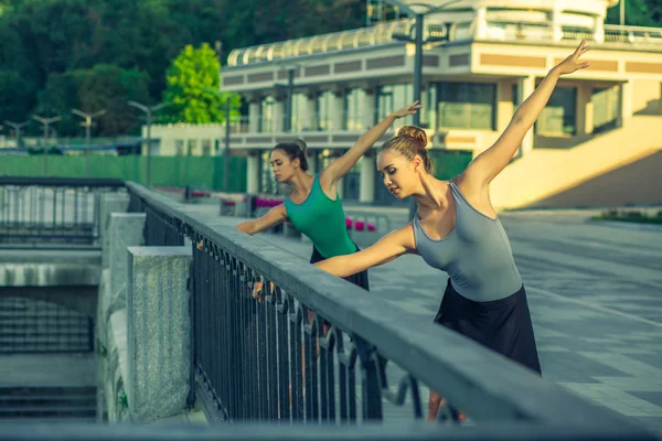 Two young beautiful twin sister dancing ballet in the city.