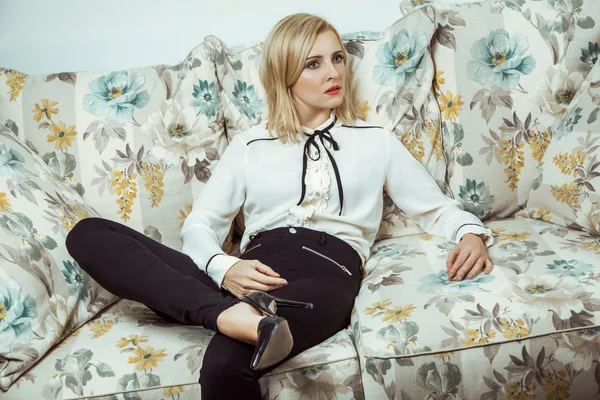 Beautiful young fashion caucasian blonde model posing on sofa.