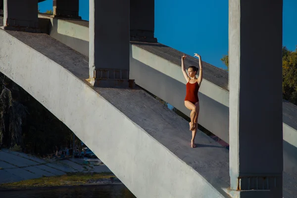 Young beautiful woman gymnast posing on bridge girder