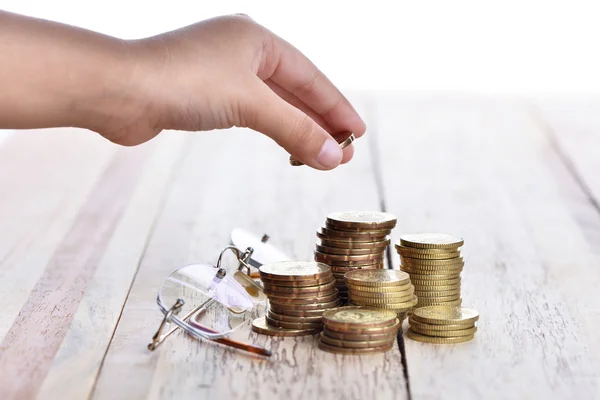 Hand put coins to stack of coins on wood table-saving concept