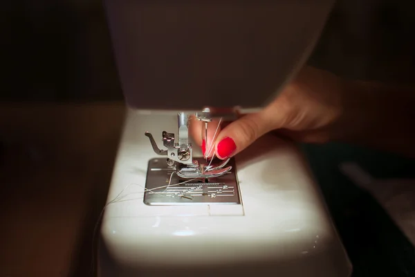 Close-up female hands sewing fabric on sewing machine