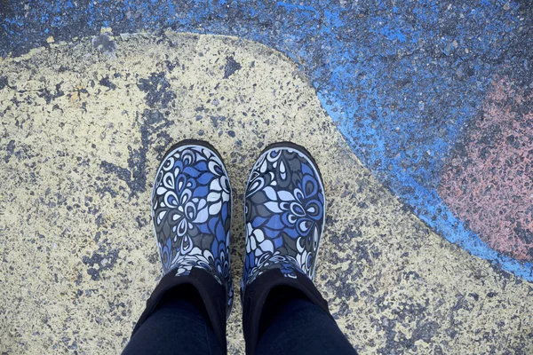 Colorful rain rubber shoes on the painted pavement