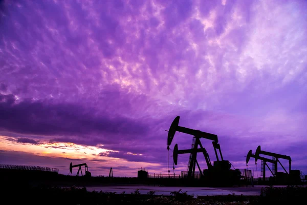 Silhouette of Oil pumps at oil field with sunset sky background