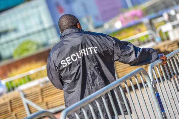 Security worker leaning over metallic fence