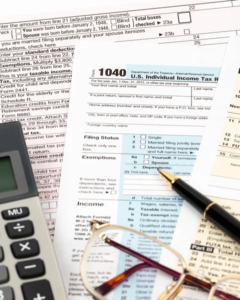 Tax form with pen, calculator, and glasses taxation concept