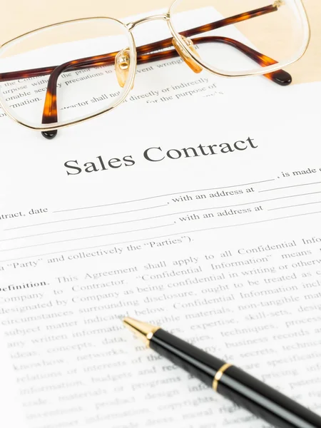 Sales contract document with glasses and pen