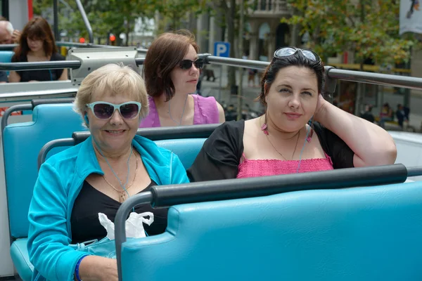 Tourist women are sitting on upper level of touristic bus.