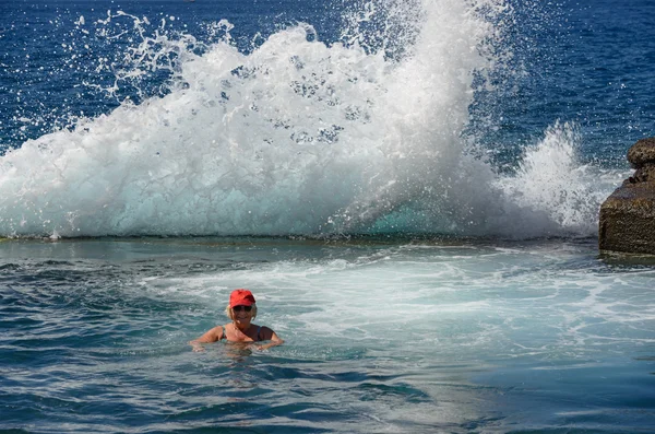 Stormy splash of ocean wave behind the senior bather.